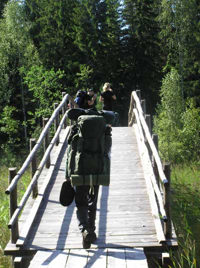 Retkeläisiä ylittämässä puusiltaa metsässä.